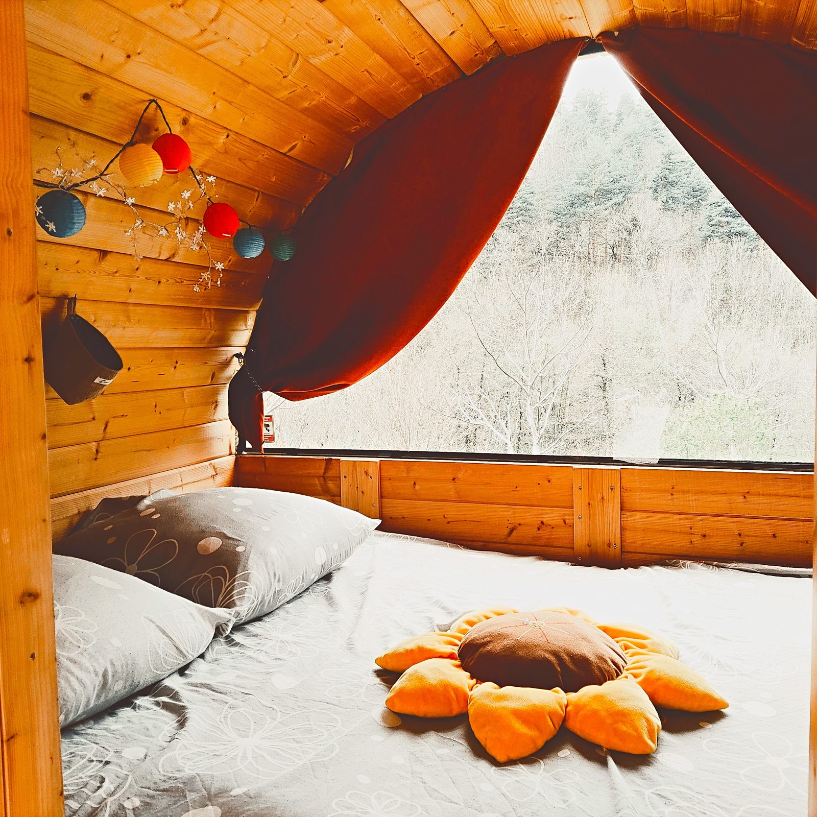 Intérieur de la cabane tonneau, lit double et fenêtre sur la nature