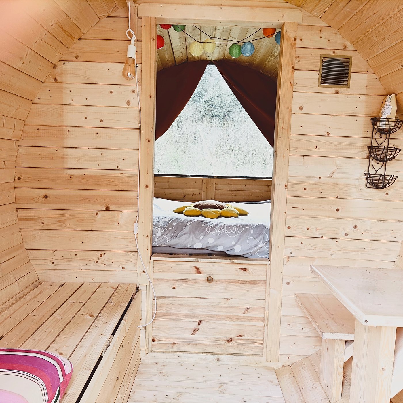 Intérieur de la cabane tonneau, lit et lampions colorés