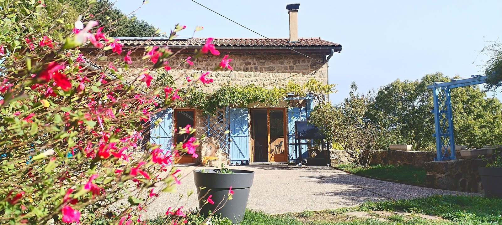 Façade en pierre de la maison, avec ses volets bleus